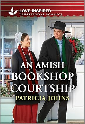 A man and woman, dressed in traditional Amish attire, stand smiling outside a bookshop. A festive wreath hangs on the door, suggesting a warm, romantic setting.