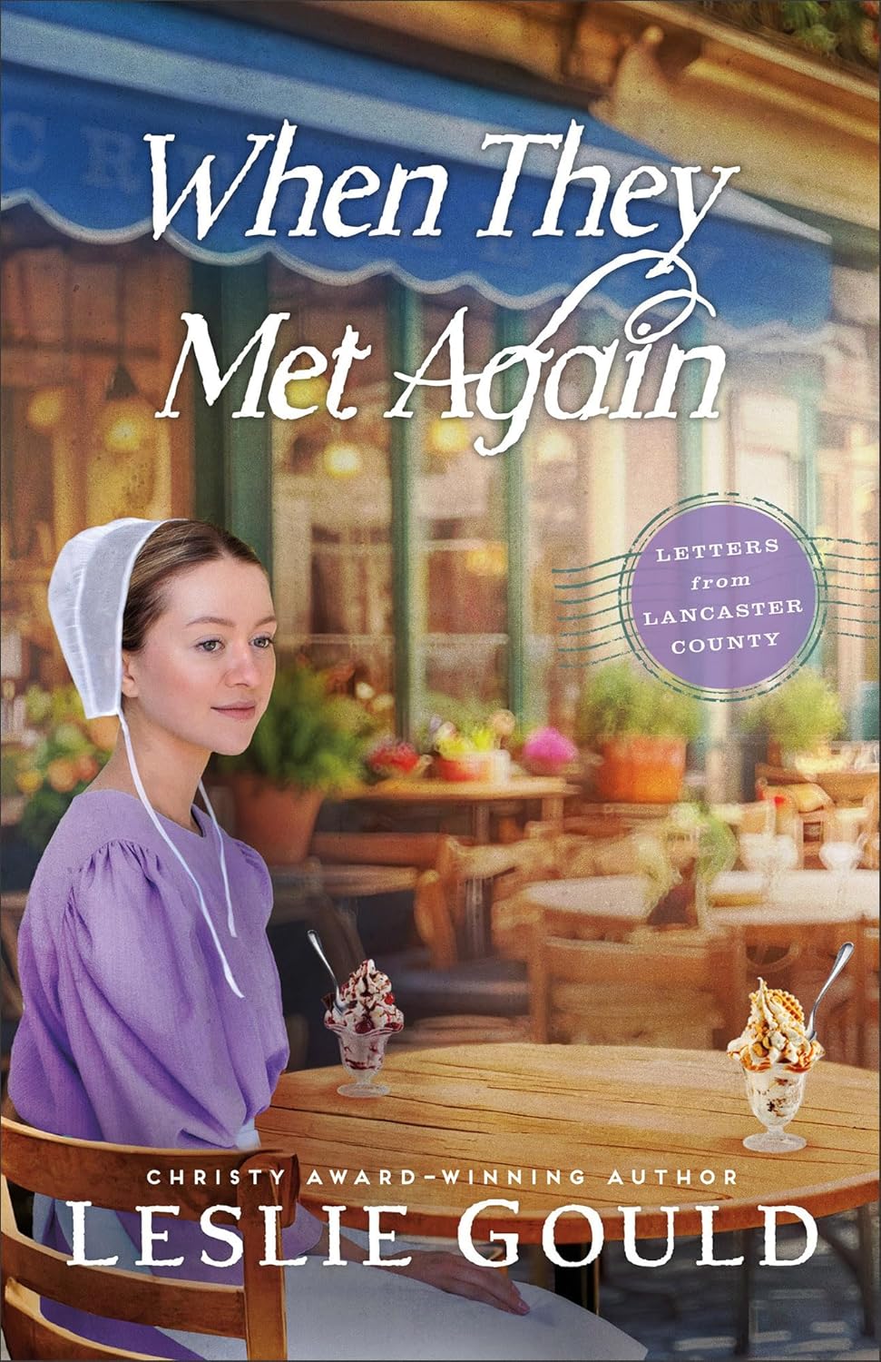 Cover of "When They Met Again" by Leslie Gould. A woman in a white bonnet and purple dress sits at an outdoor cafe table, evoking a warm, nostalgic feel.